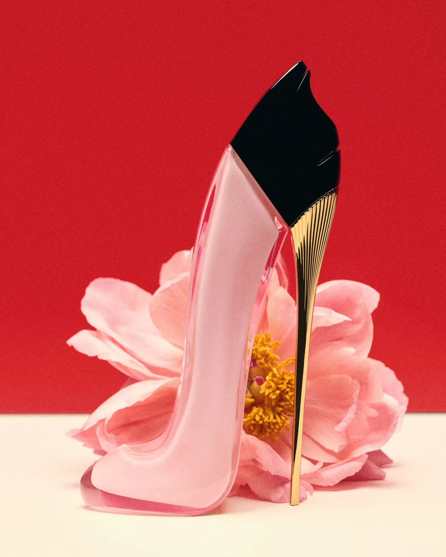 Flacon escarpin rose Good Girl Blush de Carolina Herrera posé contre une fleur rose sur fond rouge