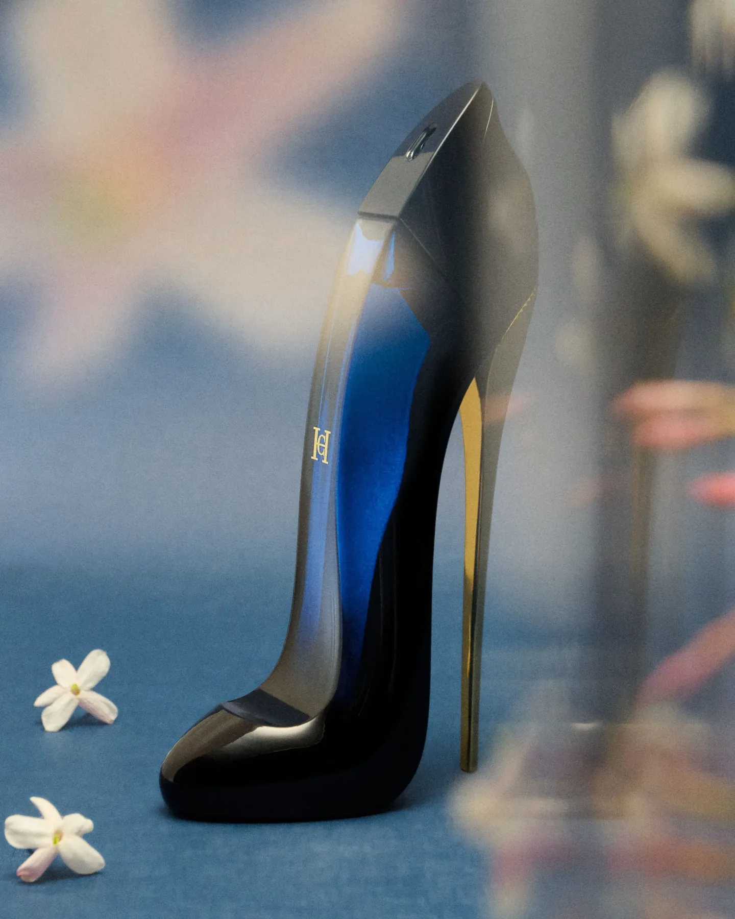 Flacon Good Girl de Carolina Herrera en forme d'escarpin bleu nuit à talon doré, petites fleurs blanches posées autour