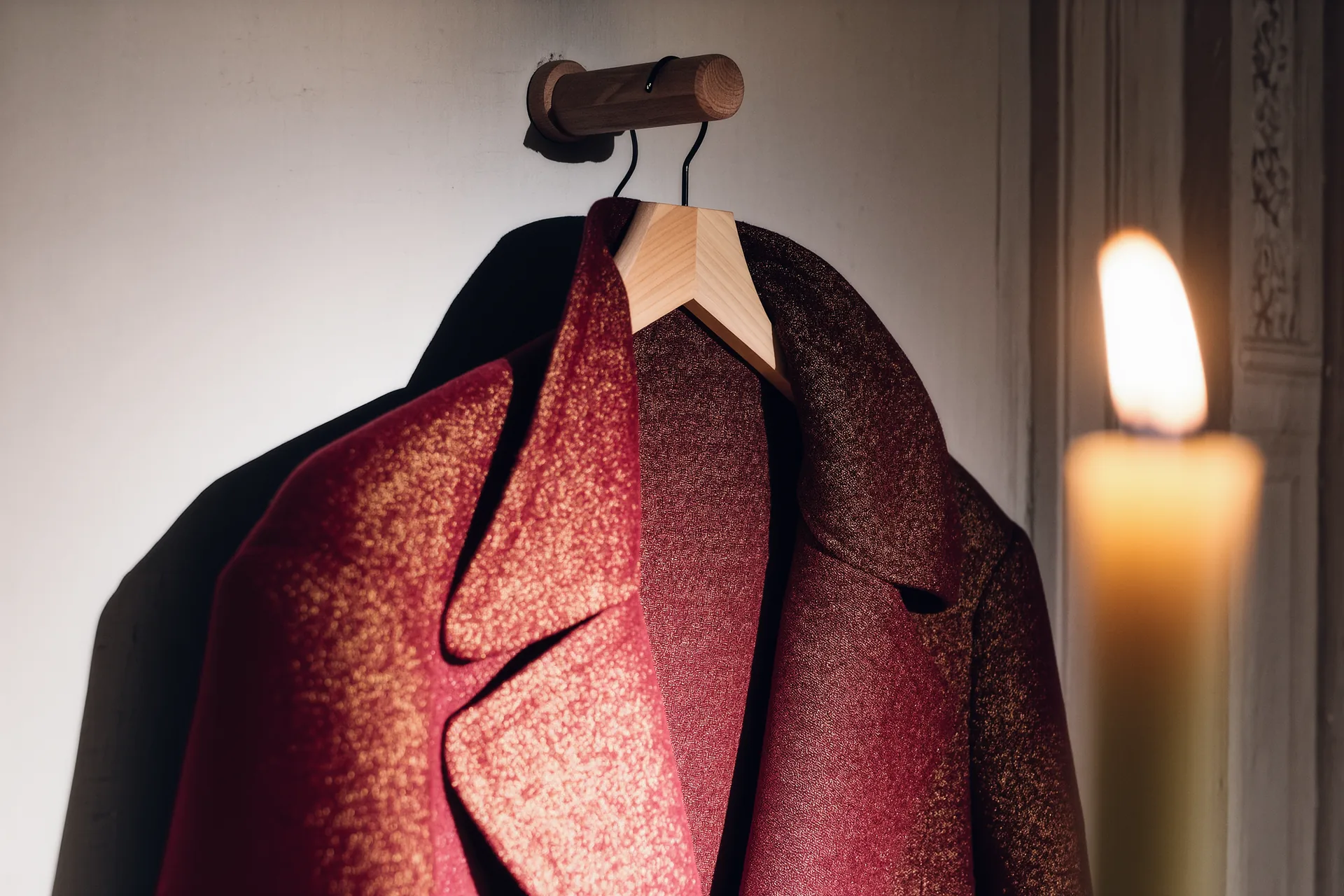 Détail d'un manteau de laine suspendu sur un cintre en bois dans une penderie épurée.
