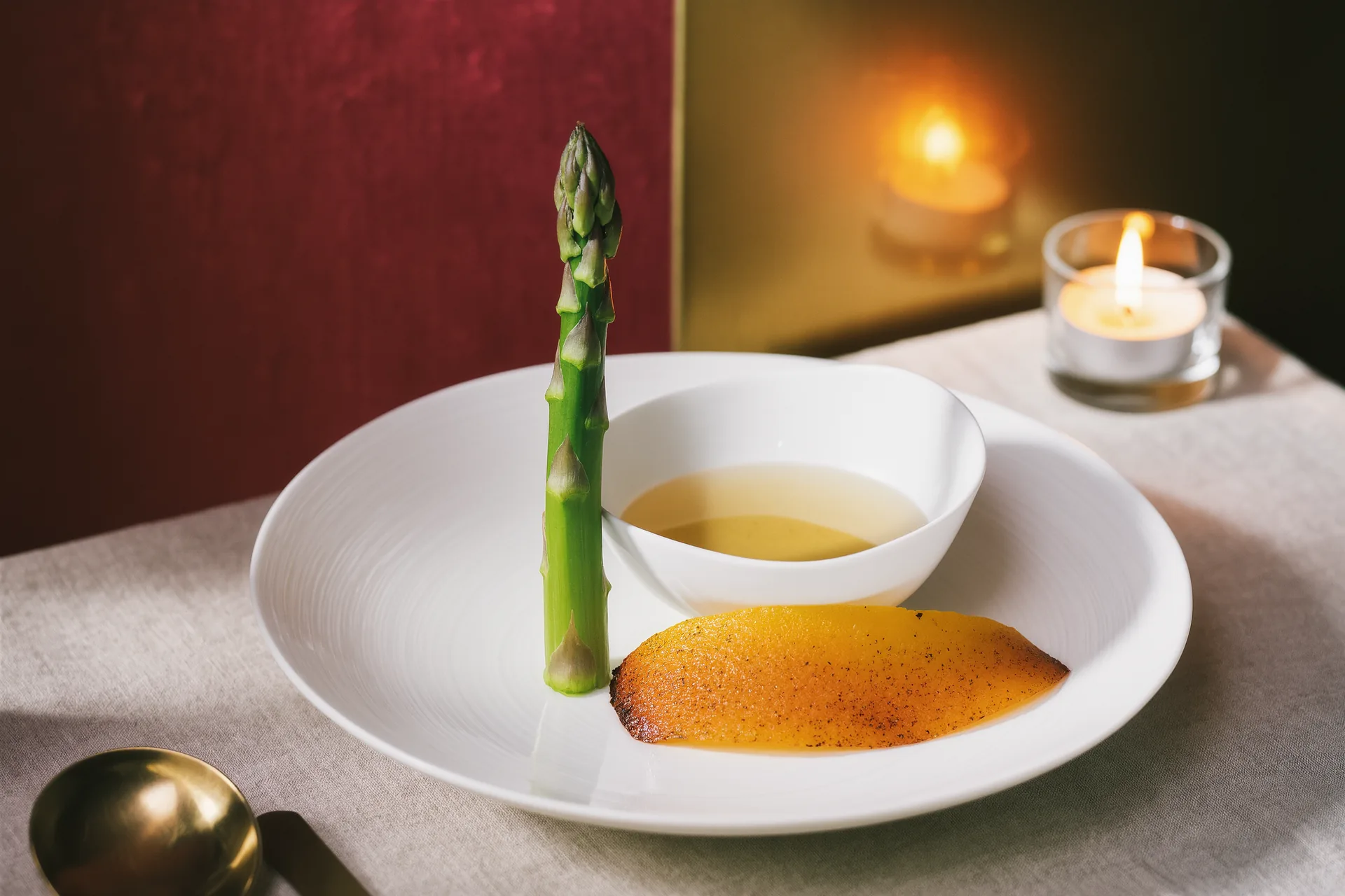 Assiette épurée mêlant légumes entiers, épluchures caramélisées et bouillon d'os dans une lumière naturelle.