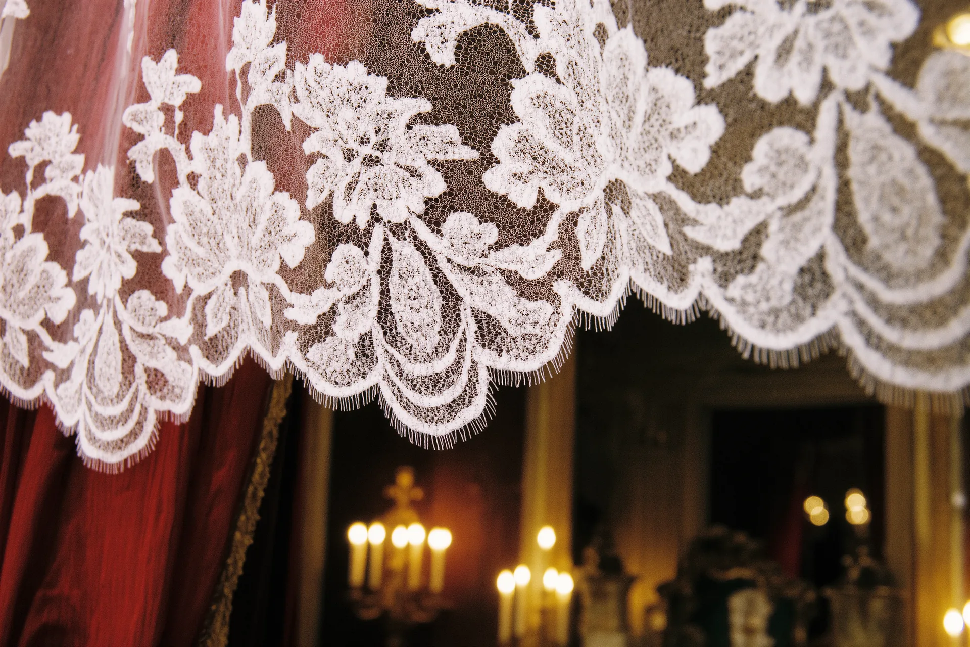 Gros plan sur une dentelle blanche tendue à contre-jour, motif floral ajouré