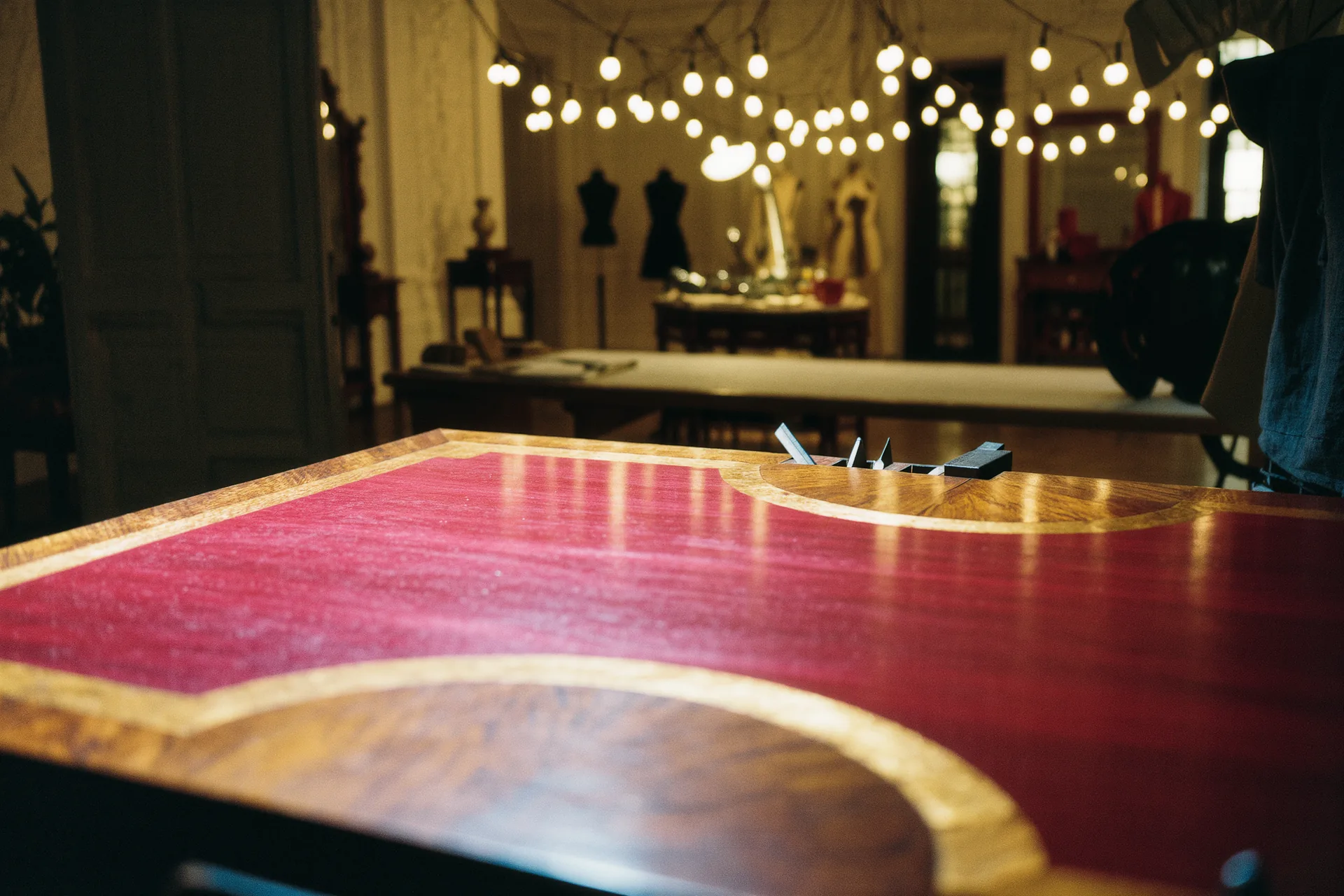 Établi de marqueteur avec placages de bois contrastés et scie fine, lumière d'atelier