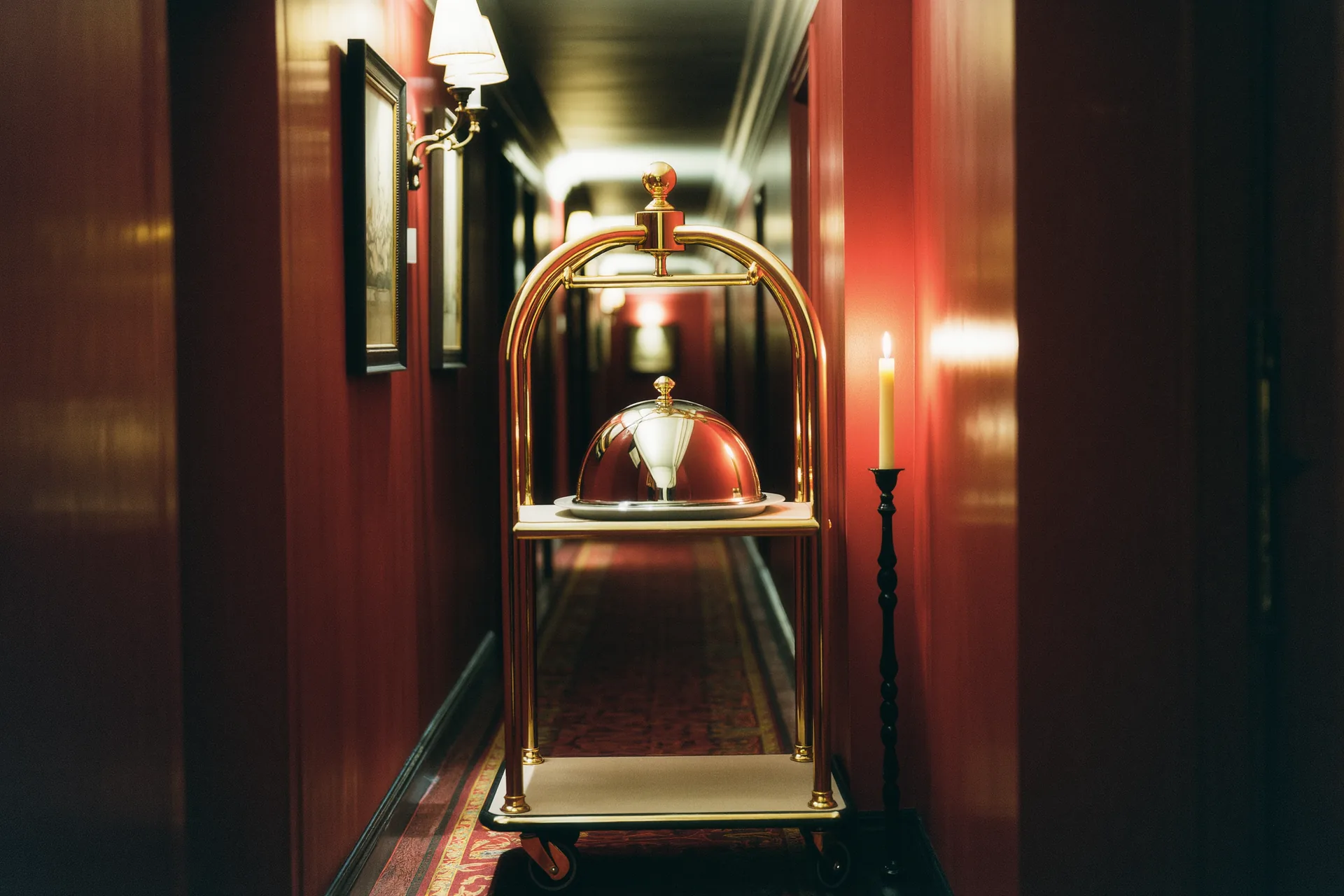 Chariot de room service dressé avec cloches argentées dans un couloir d'hôtel feutré