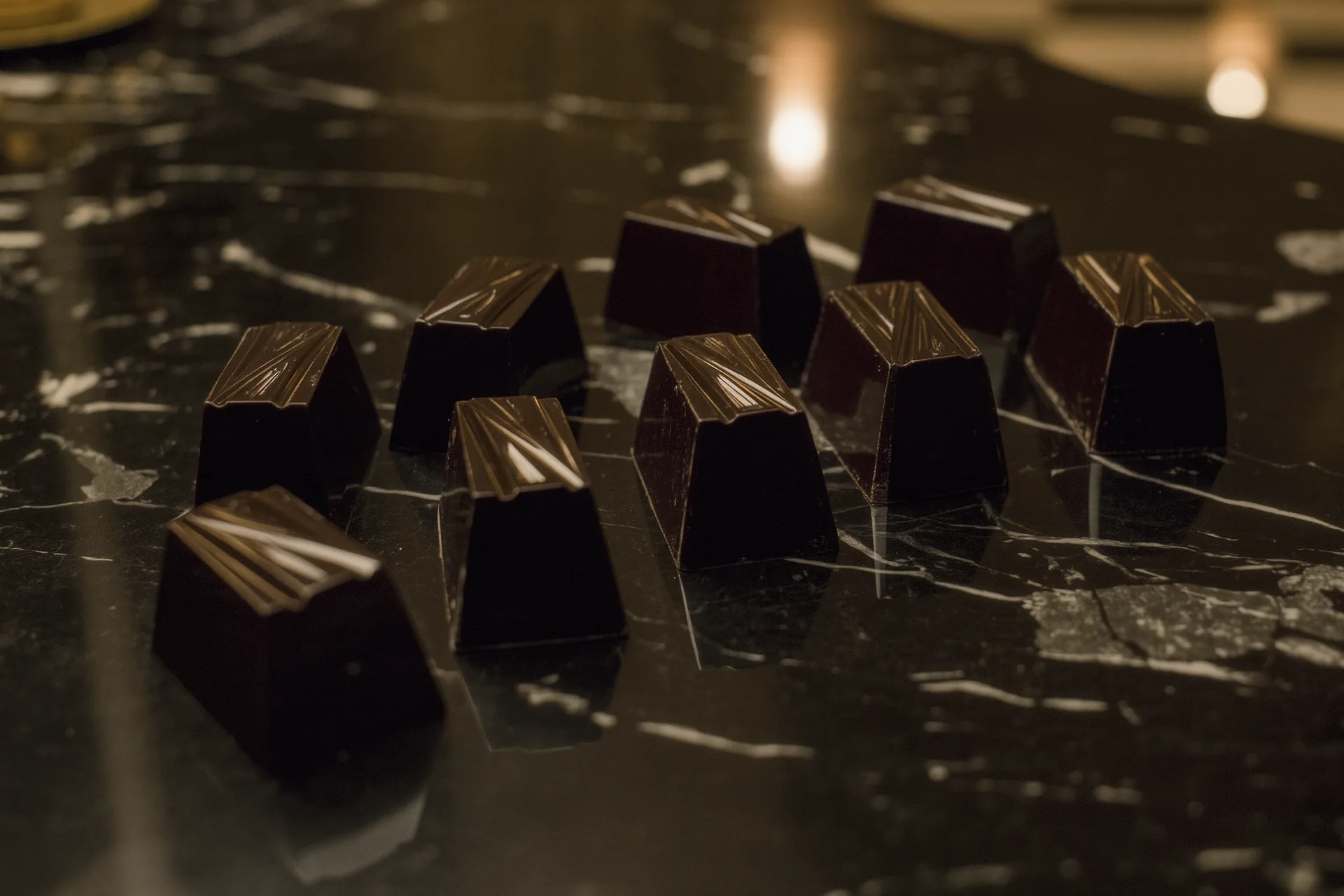 Carrés de chocolat noir grand cru disposés sur une surface sombre en marbre