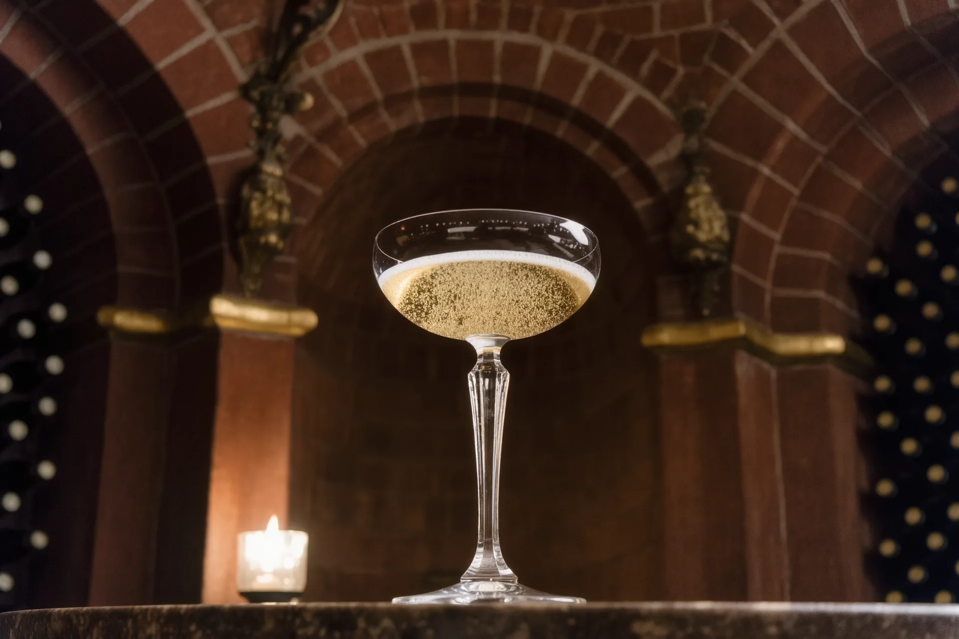 Coupe de champagne à contre-jour, bulles fines sur fond de cave voûtée