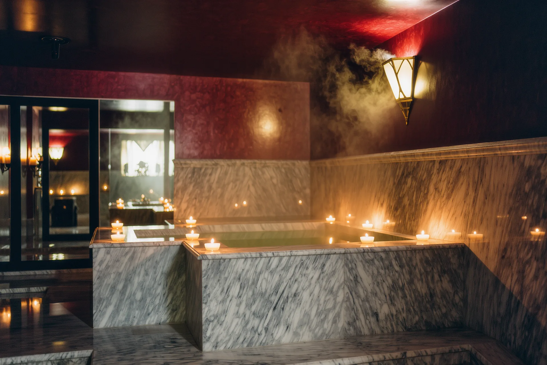 Salle de hammam en marbre baigné de vapeur et de lumière tamisée