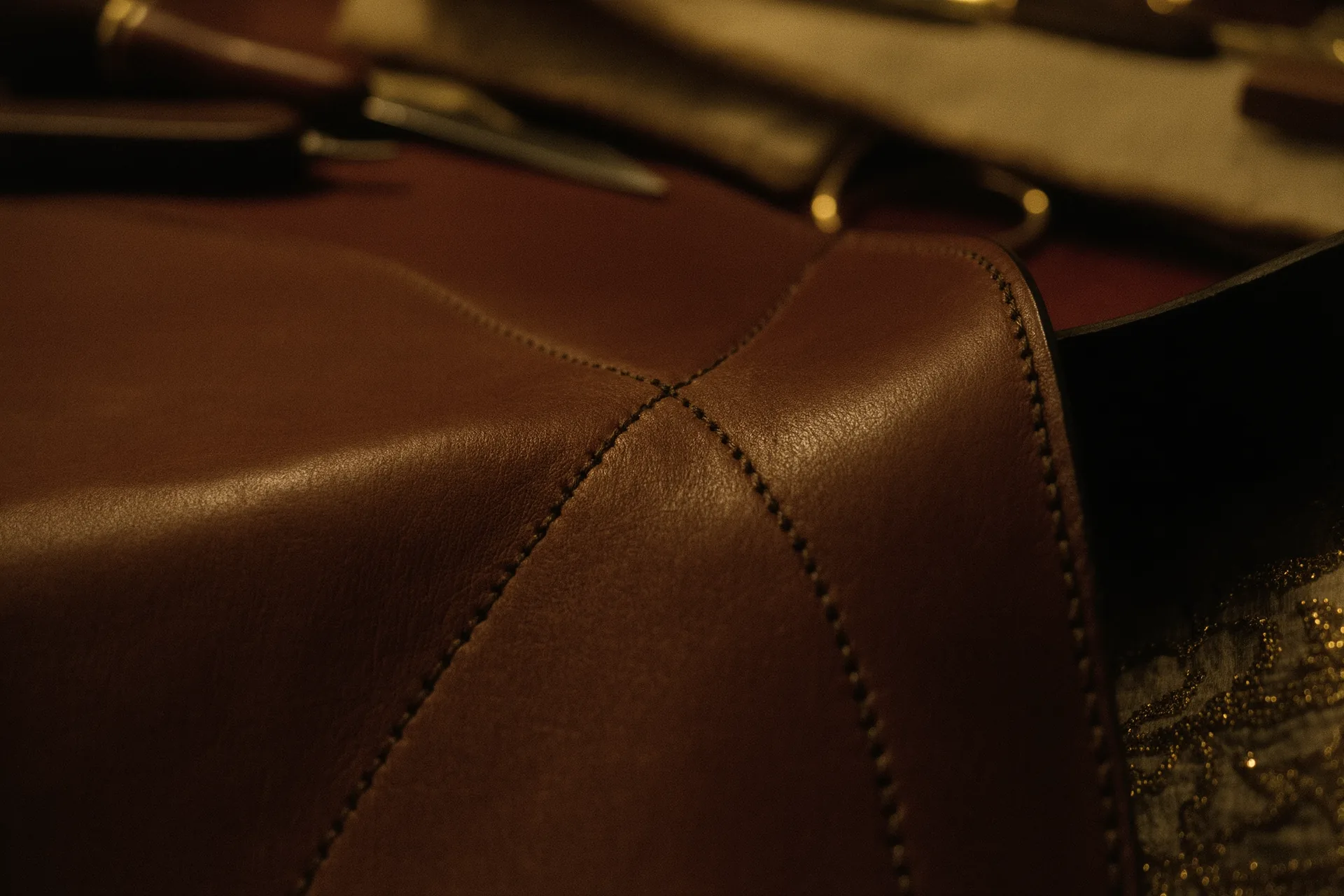 Gros plan sur une couture à la main sur un cuir souple couleur cognac