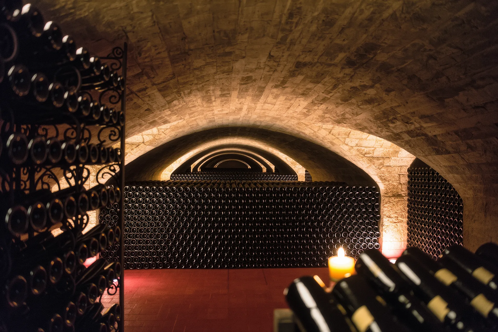 Cave à vin voûtée en pierre, casiers de bouteilles couchées dans la pénombre