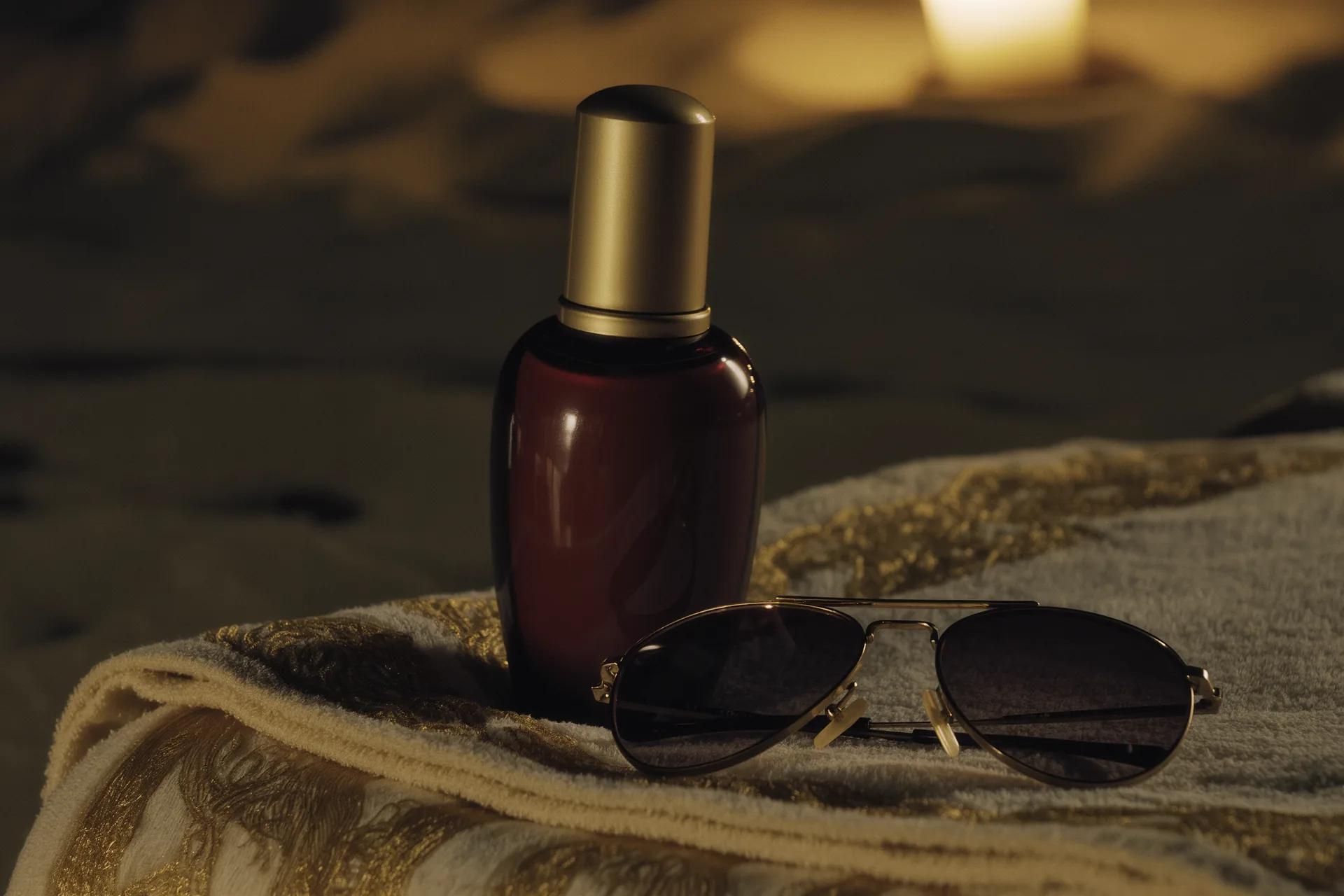 Flacon de protection solaire et lunettes de soleil posés sur une serviette de plage
