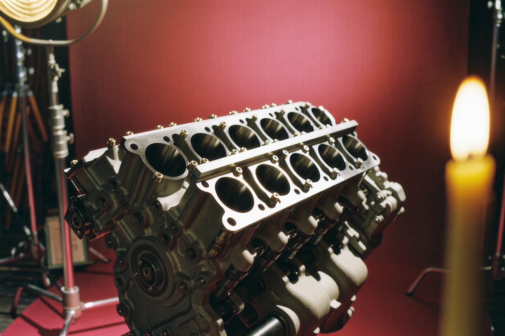 Photographie rapprochée d'un moteur V12 aux culasses polies, capot ouvert en studio.